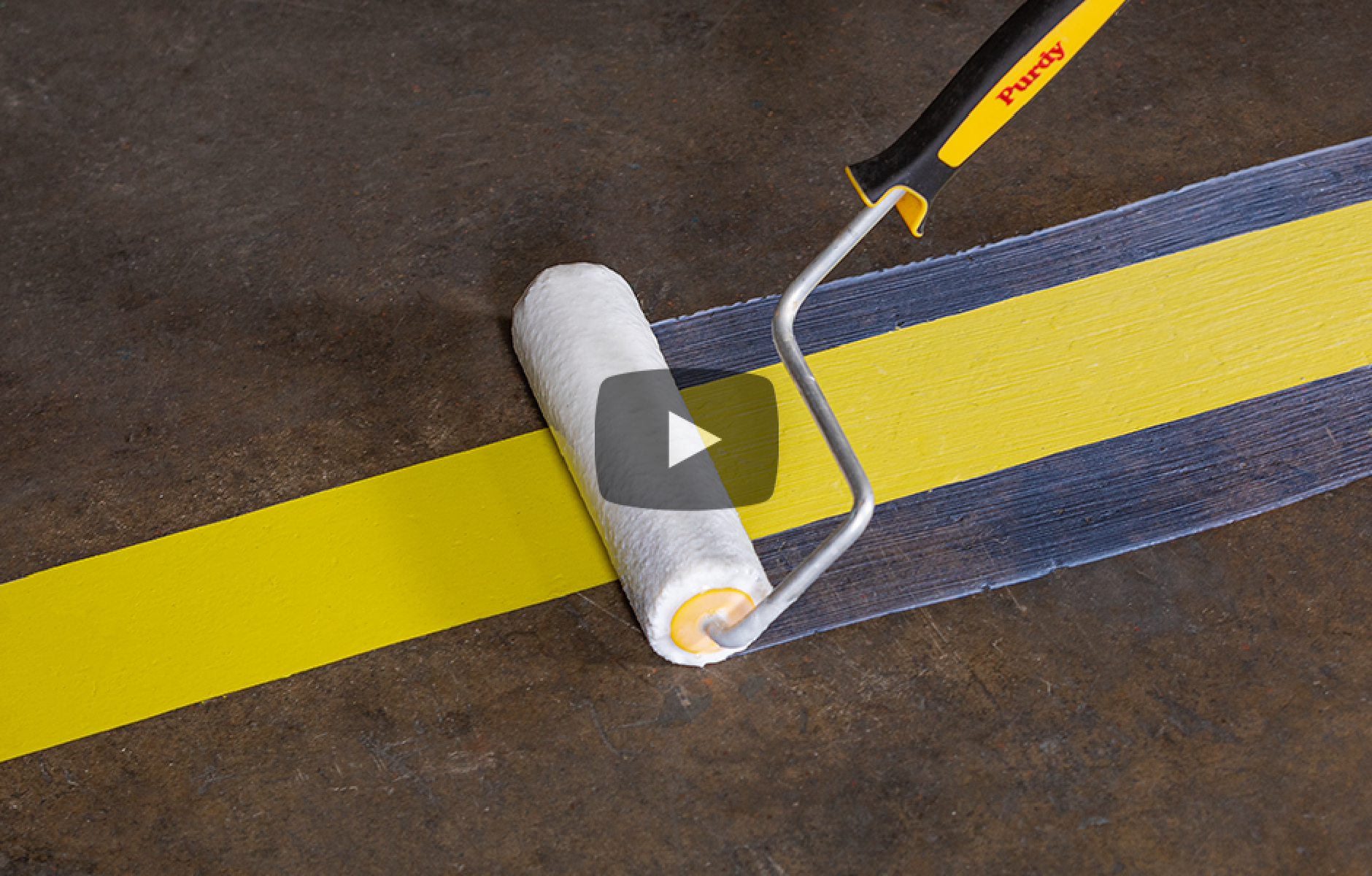 applying VersaShield with a roller over top of yellow floor stripe